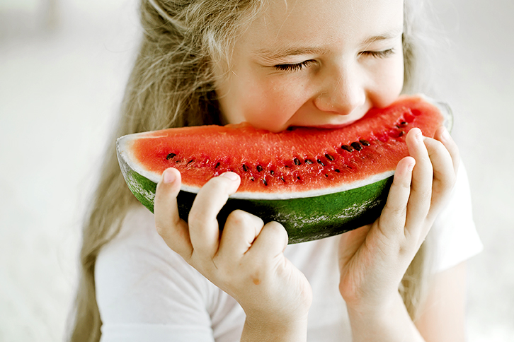 Small girl biting into a piece of watermelon Small girl biting into a piece of watermelon