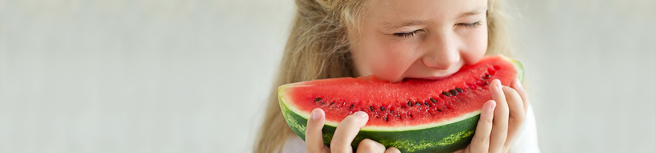 Small girl biting into a piece of watermelon Small girl biting into a piece of watermelon